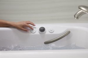 Woman adjusts control panel of bathtub..