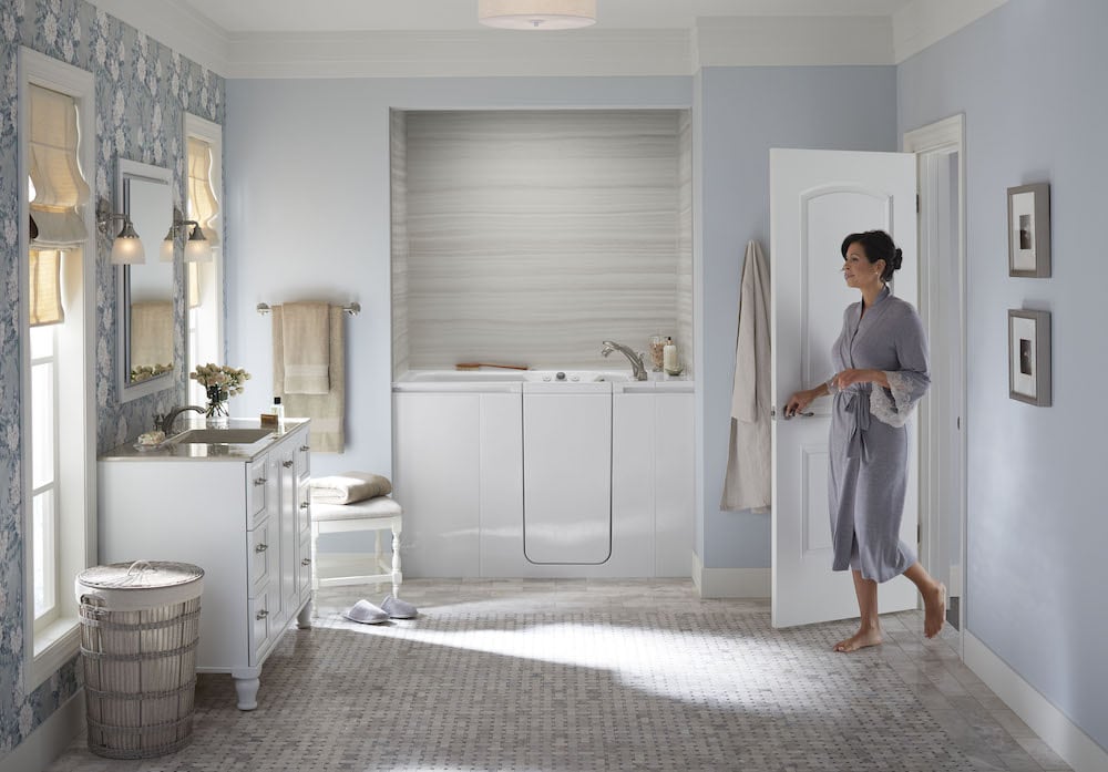 woman walking into a bathroom with a walk-in tub