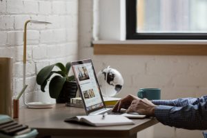 Man types on computer in home office.