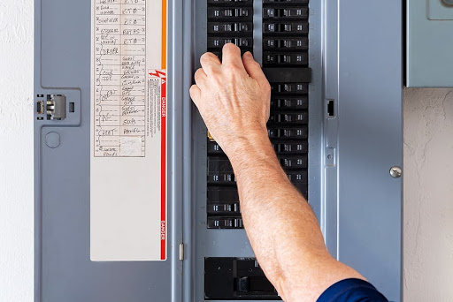 Person's hand in circuit breaker trying to fix electrical problem