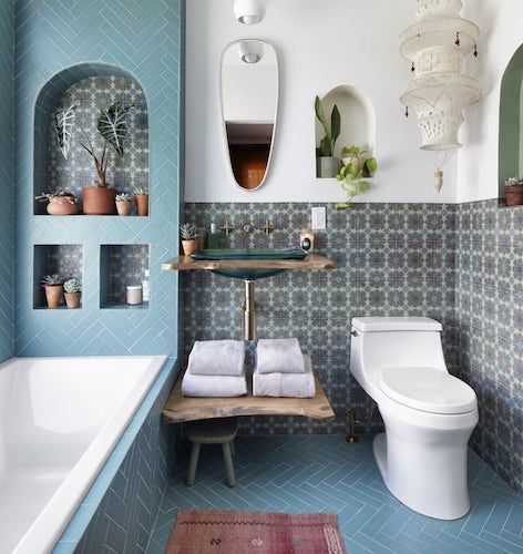 Bathroom with turquoise painted walls, white tub, and stone walls