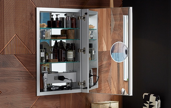 Mirrored medicine cabinet hung on a wooden wall with an electrical socket inside.