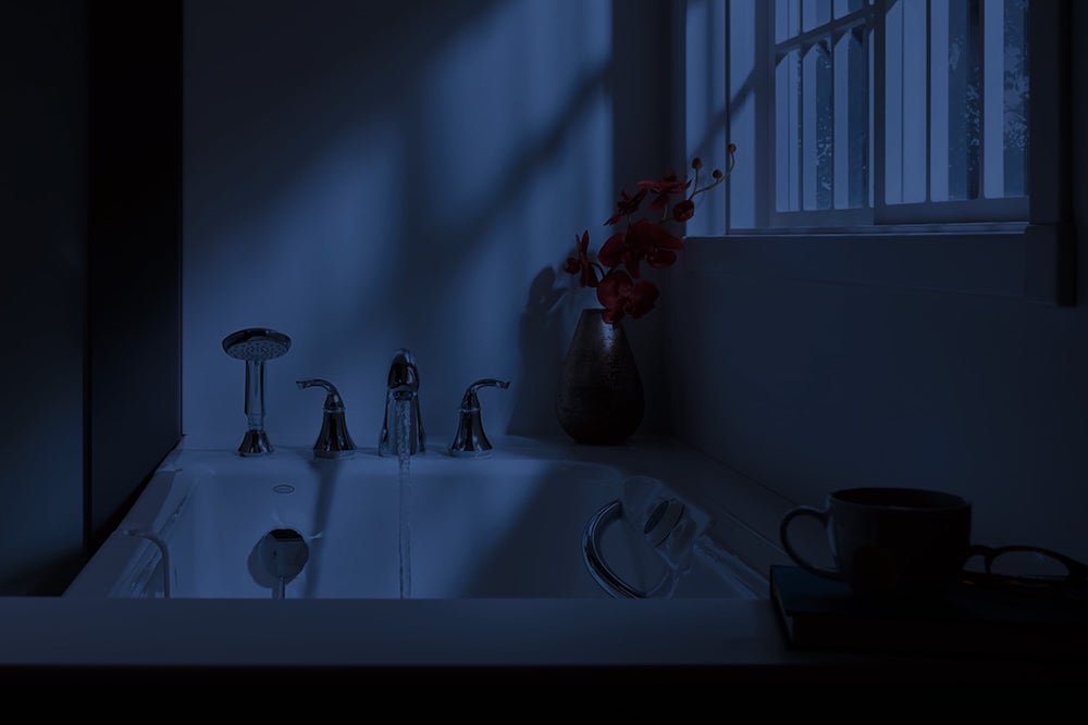 Bathtub at night with water running from faucet and moonlight shining into window