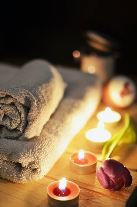 Bathroom towels on bathtub ledge with candles