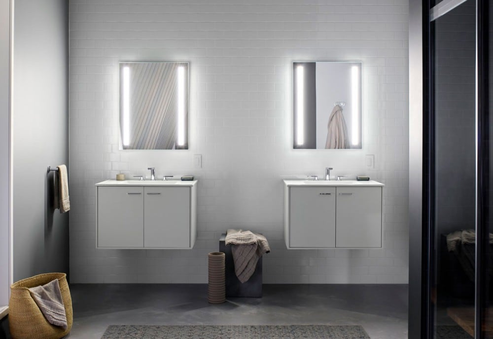 Lighted wall mirrors mounted above split bathroom vanities