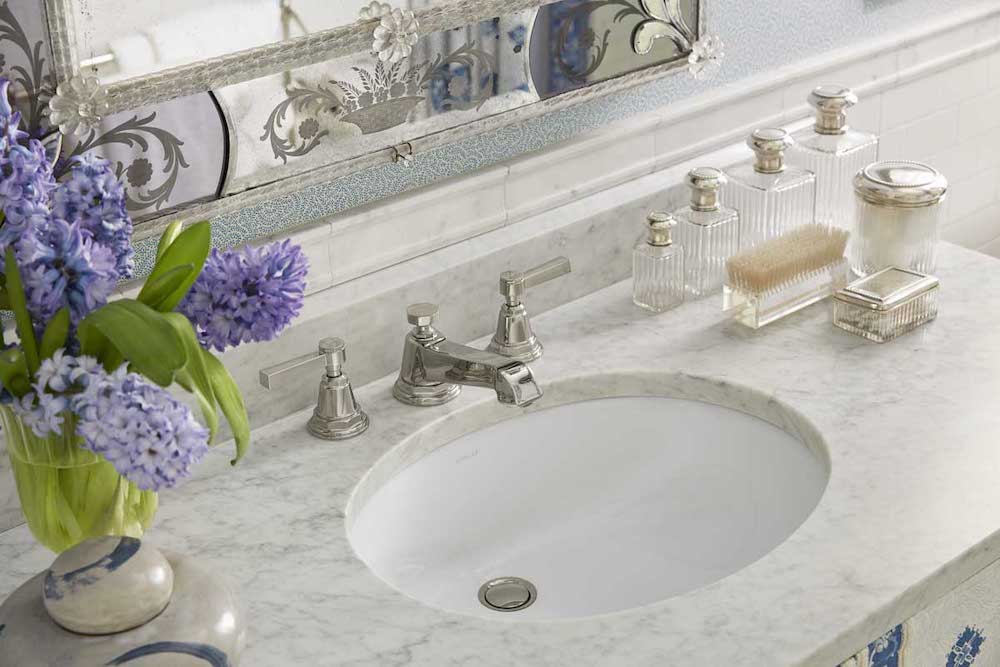 Marble bathroom countertop displaying purple flowers