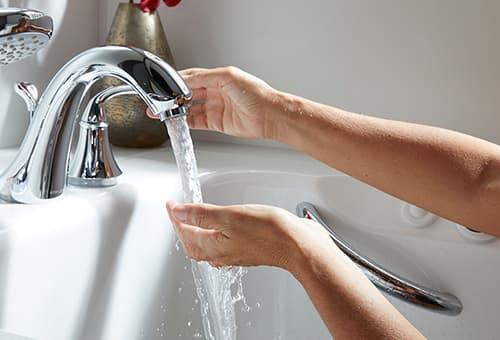 Hands under faucet in bathtub