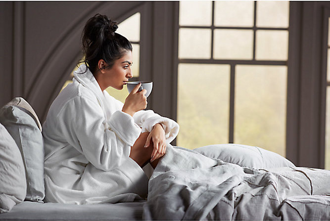 Person in bed drinking coffee in bathrobe