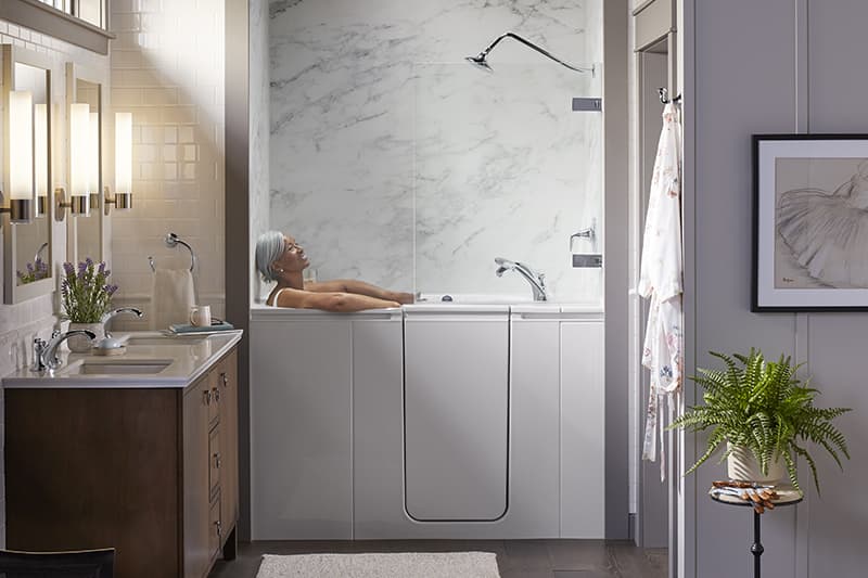 Woman relaxing in KOHLER Walk-In Bath with Shower Package