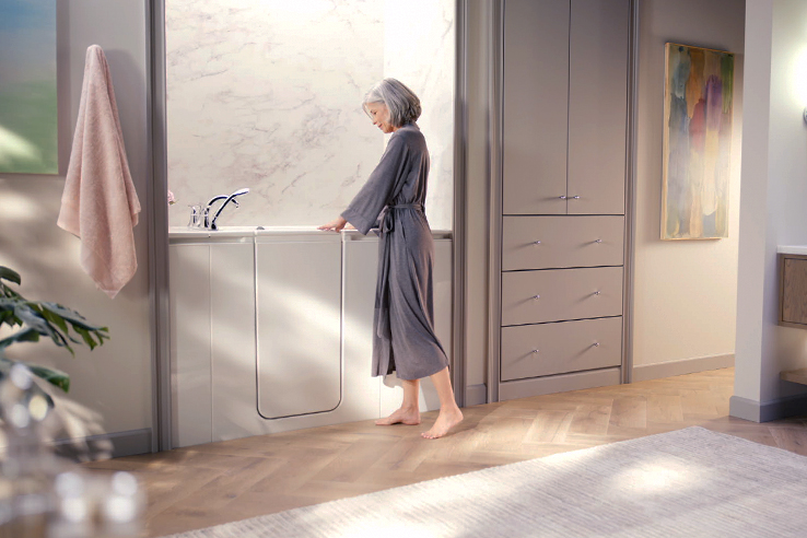 Woman standing outside Walk-In Bath on wood flooring