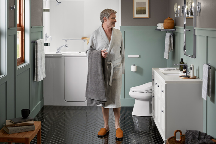 Man holding towel in bathroom.