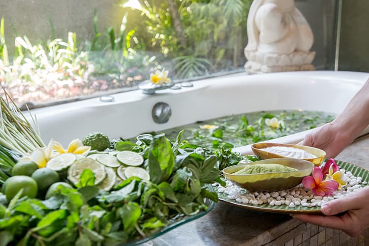 Bathtub filled with citrus such as lemons and limes as well as mint leaves and other herbal accouterments. 