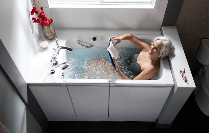 Woman in bathtub reading book at night