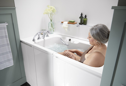 Woman massaging her knee in the KOHLER Walk-In Bath