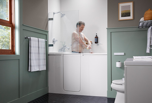 Man washing his body in the Walk-In Bath featuring the Shower Package