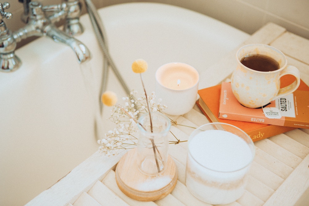 bath tray over a tub with a mug of tea, water and books