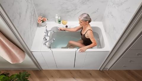ariel view of woman in the walk-in bath using inside grab bar and outside handrail to get up